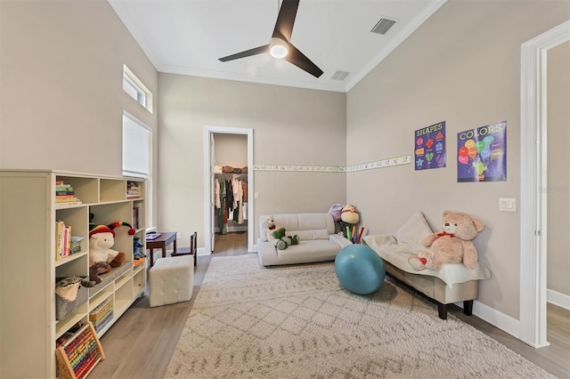 playroom with ornamental molding, wood finished floors, ceiling fan, and baseboards