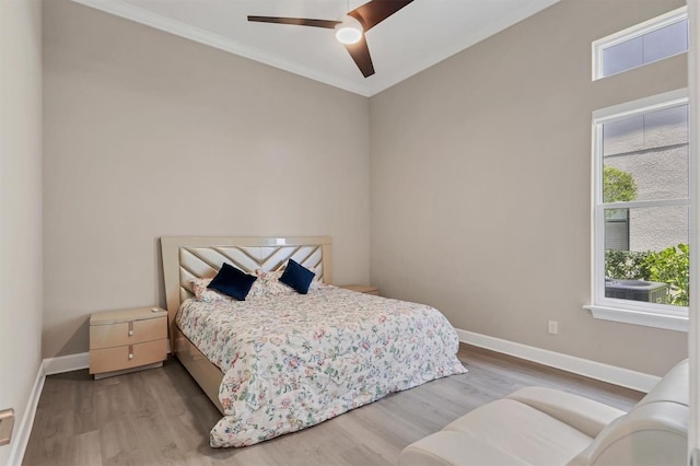 bedroom with baseboards, light wood-style flooring, ornamental molding, and ceiling fan