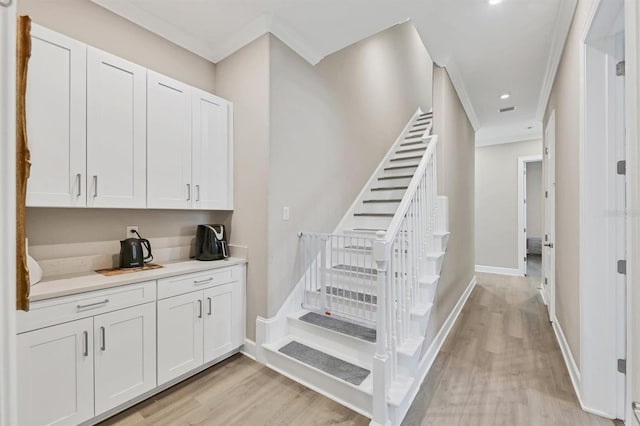 staircase with wood finished floors, crown molding, baseboards, and recessed lighting