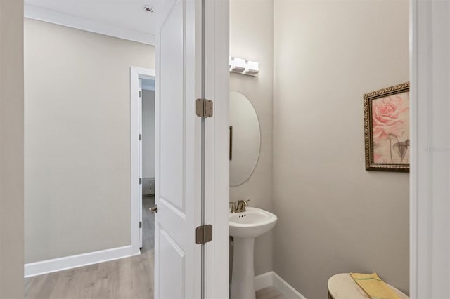 half bathroom featuring baseboards, wood finished floors, a sink, and toilet