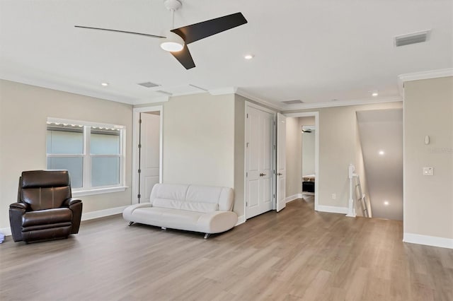 sitting room with an upstairs landing, light wood finished floors, ornamental molding, baseboards, and a ceiling fan