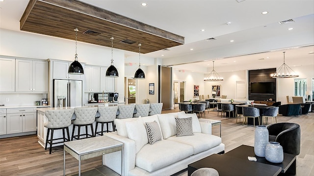 living room with recessed lighting, wood finished floors, a towering ceiling, and a chandelier
