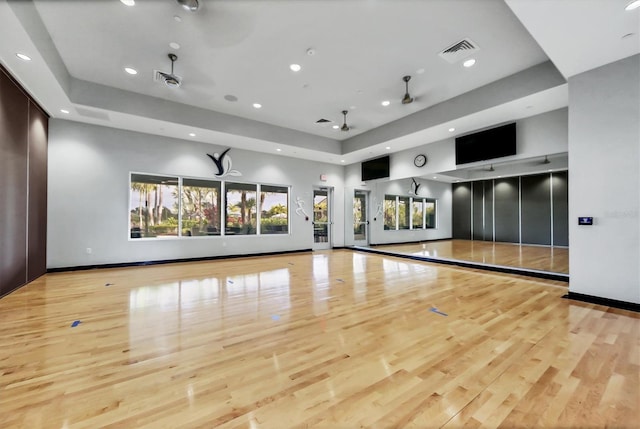 unfurnished living room featuring recessed lighting, wood finished floors, a raised ceiling, baseboards, and ceiling fan