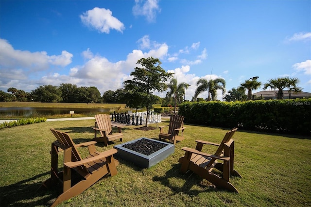 view of grassy yard with a fire pit and a water view