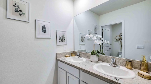 bathroom with toilet and double vanity
