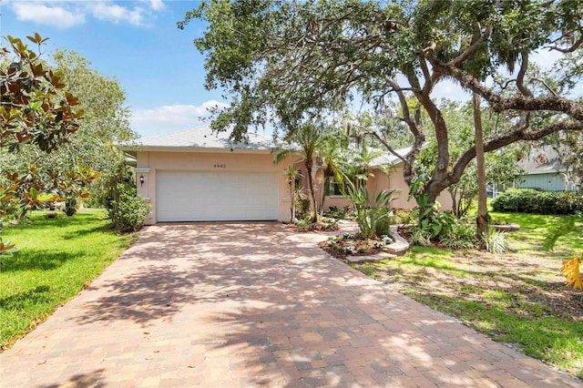 4443 Robin Hood Trl W, Sarasota, FL 34232 - obstructed view of property featuring stucco siding, decorative driveway, a front yard, and an attached garage