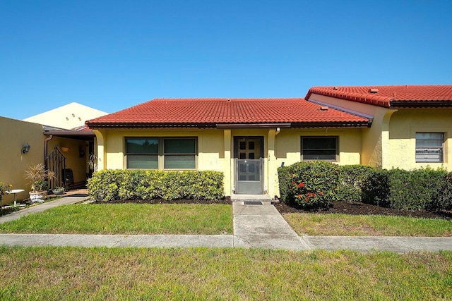 1314 57th St W Unit 1314, Bradenton, FL 34209 - view of front of home with a tiled roof, a front lawn, and stucco siding