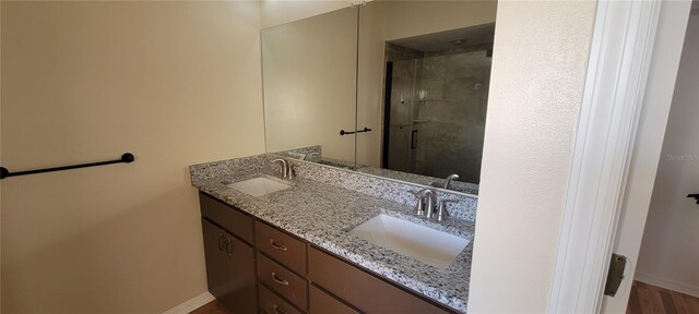 7102 52nd Dr E, Bradenton, FL 34203 - bathroom featuring baseboards, double vanity, and a tile shower