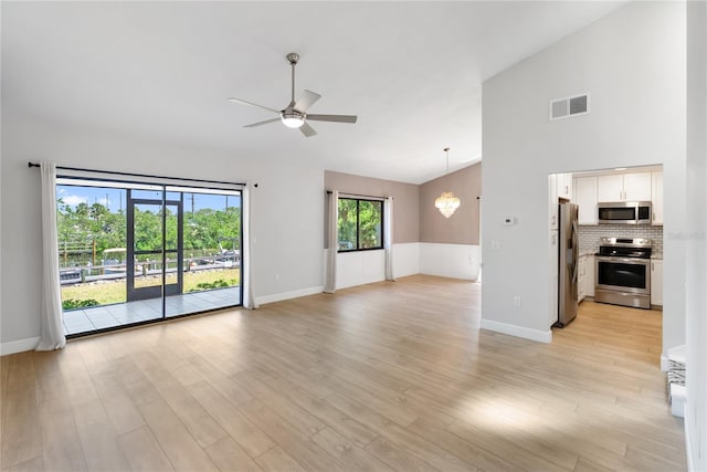 709 Sorrento Inlt Unit 709, Nokomis, FL 34275 - unfurnished living room with ceiling fan, light wood finished floors, baseboards, lofted ceiling, and a chandelier