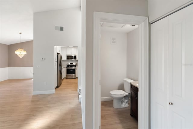 709 Sorrento Inlt Unit 709, Nokomis, FL 34275 - bathroom featuring wood finished floors, toilet, a chandelier, vanity, and backsplash