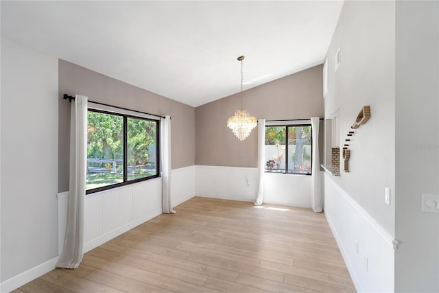 709 Sorrento Inlt Unit 709, Nokomis, FL 34275 - empty room featuring healthy amount of natural light, light wood-style flooring, a wainscoted wall, a chandelier, and vaulted ceiling