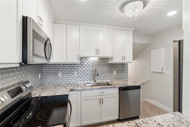 709 Sorrento Inlt Unit 709, Nokomis, FL 34275 - kitchen featuring stainless steel appliances, a sink, white cabinets, and light wood-style floors