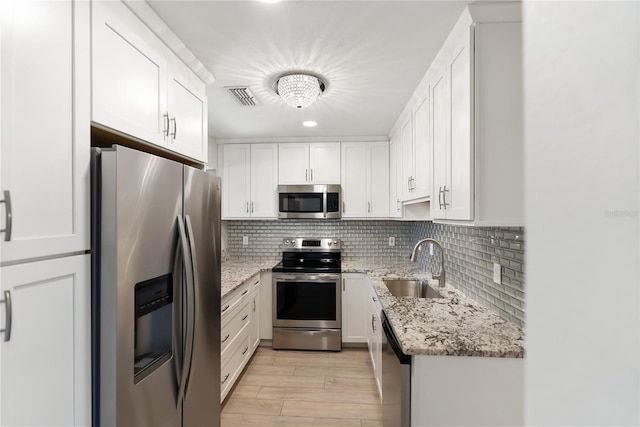 709 Sorrento Inlt Unit 709, Nokomis, FL 34275 - kitchen with stainless steel appliances, a sink, light stone counters, decorative backsplash, and white cabinets