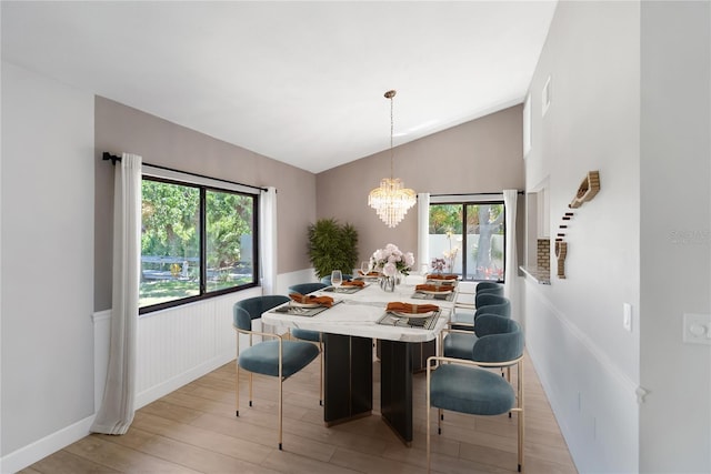 709 Sorrento Inlt Unit 709, Nokomis, FL 34275 - dining area featuring wood finished floors, a chandelier, vaulted ceiling, and a wainscoted wall