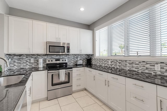 603 Cedars Ct, Longboat Key, FL 34228 - kitchen with appliances with stainless steel finishes, a sink, light tile patterned floors, decorative backsplash, and white cabinetry