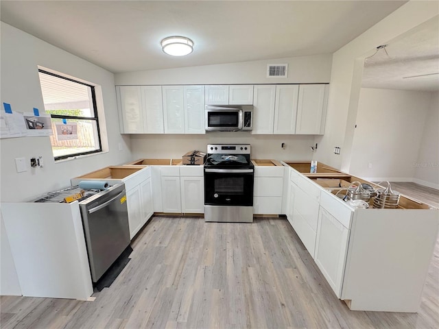 1902 24th Ave W, Bradenton, FL 34205 - kitchen featuring stainless steel appliances, light wood-type flooring, a peninsula, and white cabinets