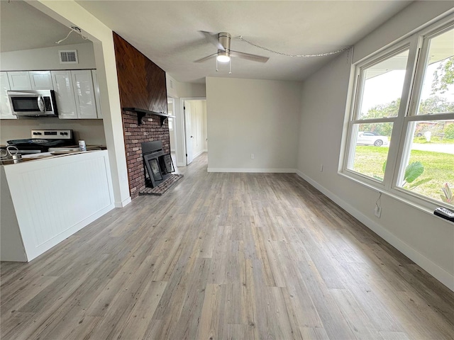 1902 24th Ave W, Bradenton, FL 34205 - unfurnished living room featuring light wood-style flooring, a ceiling fan, baseboards, and a brick fireplace