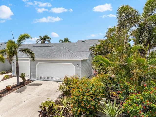view of side of property with an attached garage, driveway, and roof with shingles