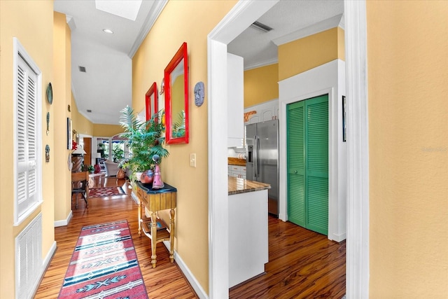 corridor with wood finished floors, a skylight, baseboards, and recessed lighting