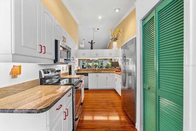 kitchen with appliances with stainless steel finishes, white cabinets, light wood-style flooring, crown molding, and a sink