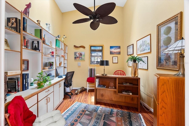 office featuring baseboards, wood finished floors, ceiling fan, and a high ceiling