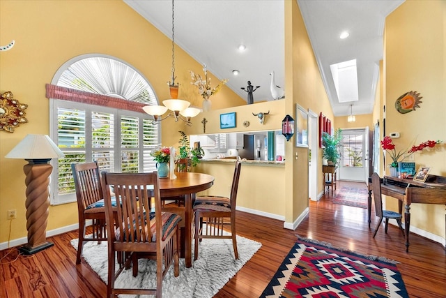 dining area with high vaulted ceiling, baseboards, wood finished floors, a chandelier, and a skylight