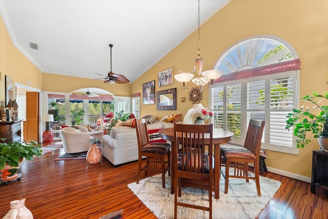 dining room with crown molding, ceiling fan, high vaulted ceiling, a chandelier, and wood finished floors