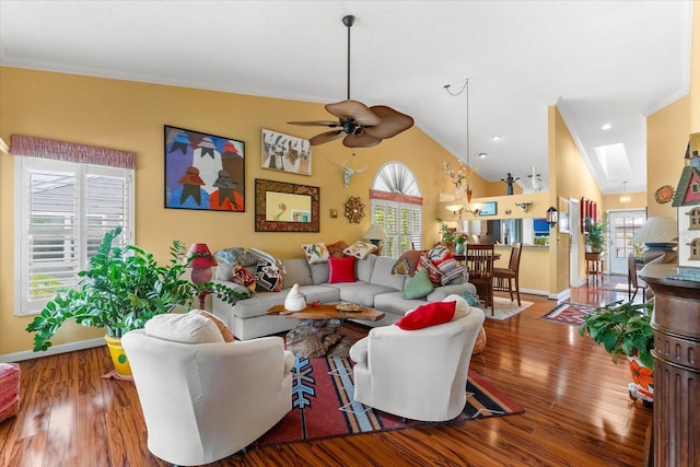 living room with plenty of natural light, ceiling fan, wood finished floors, crown molding, and lofted ceiling