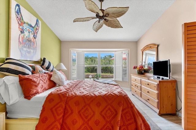 bedroom with a textured ceiling, lofted ceiling, light wood-type flooring, and ceiling fan