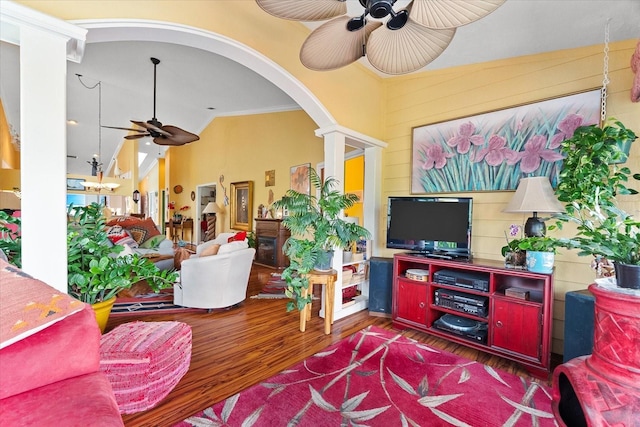 living area with ceiling fan, wood finished floors, vaulted ceiling, arched walkways, and ornamental molding