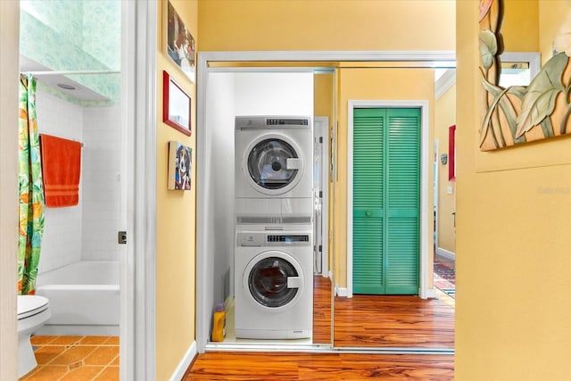 washroom with stacked washer / dryer, baseboards, and tile patterned floors