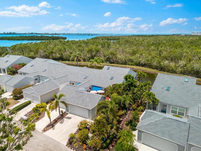 aerial view of residential area featuring a forest and a nearby body of water