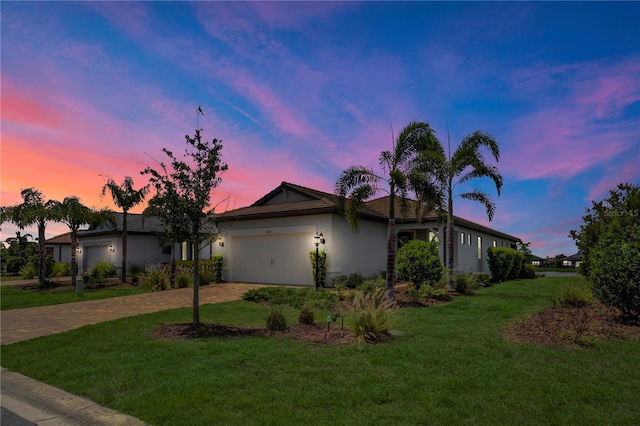 17725 Northwood Pl, Bradenton, FL 34202 - ranch-style house with decorative driveway, stucco siding, a garage, and a front lawn