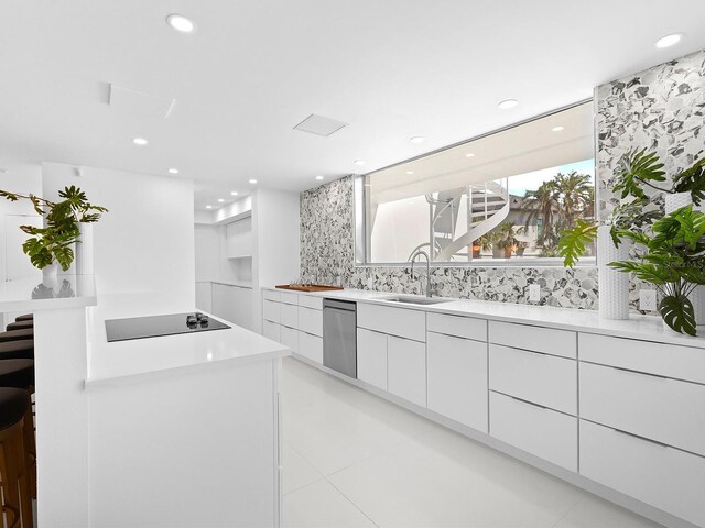 7647 Sanderling Rd, Sarasota, FL 34242 - kitchen featuring black electric cooktop, modern cabinets, a sink, dishwasher, and white cabinetry
