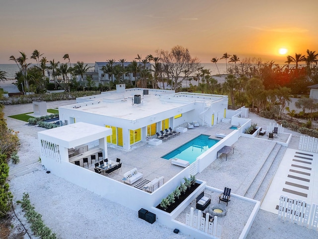 7647 Sanderling Rd, Sarasota, FL 34242 - back of property at dusk with a community pool, a patio area, a bar, and outdoor dining area