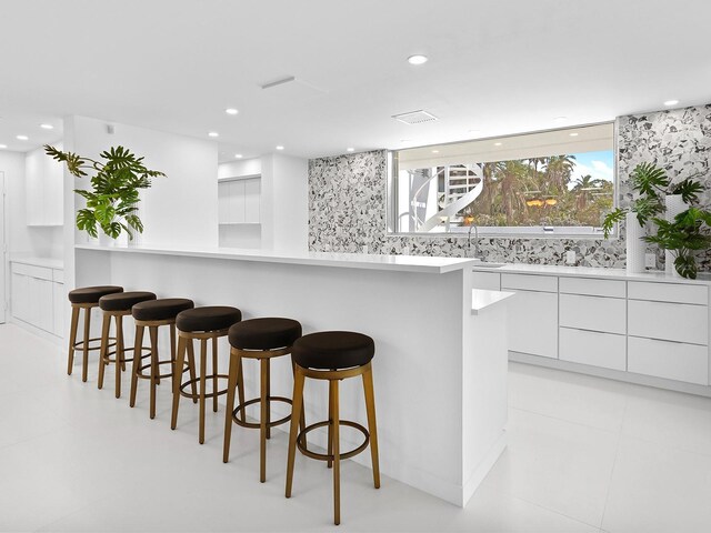 7647 Sanderling Rd, Sarasota, FL 34242 - kitchen with modern cabinets, a breakfast bar, white cabinetry, a sink, and light countertops