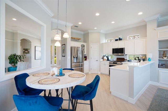 7164 Rue De Palisades Unit 5, Sarasota, FL 34238 - kitchen with stainless steel appliances, a peninsula, white cabinetry, light wood finished floors, and recessed lighting