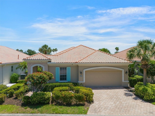 7164 Rue De Palisades Unit 5, Sarasota, FL 34238 - mediterranean / spanish-style house with an attached garage, driveway, stucco siding, a tiled roof, and central AC
