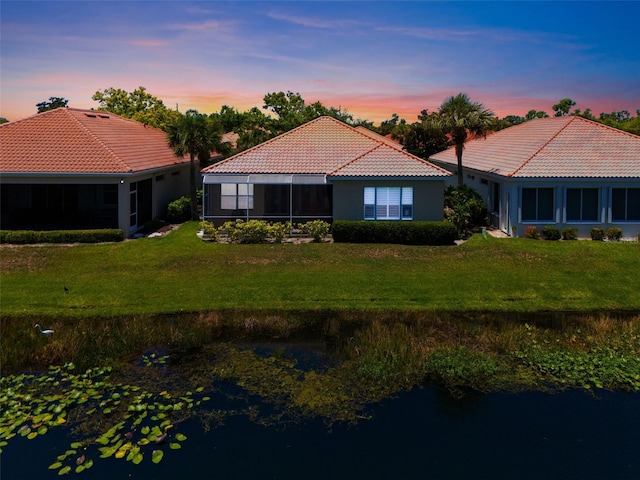 7164 Rue De Palisades Unit 5, Sarasota, FL 34238 - back of house at dusk featuring a tile roof, a yard, and stucco siding