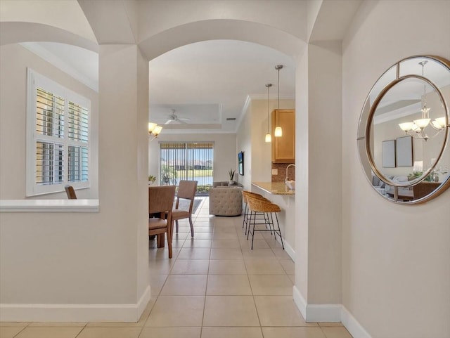 635 Chipper Dr, Sun City Center, FL 33573 - hallway with baseboards, arched walkways, a chandelier, crown molding, and light tile patterned floors