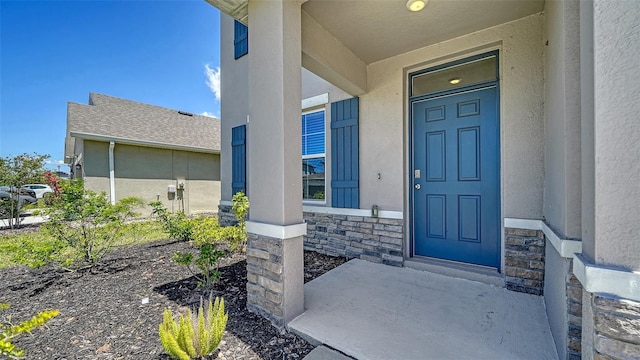 12728 Lateral Root Dr, Sarasota, FL 34238 - view of exterior entry with stone siding, stucco siding, and covered porch