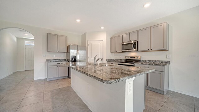 12728 Lateral Root Dr, Sarasota, FL 34238 - kitchen featuring stainless steel appliances, a sink, gray cabinetry, arched walkways, and light tile patterned floors