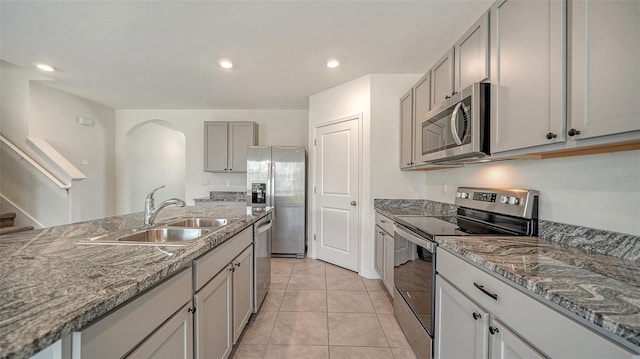 12728 Lateral Root Dr, Sarasota, FL 34238 - kitchen with stainless steel appliances, a sink, arched walkways, gray cabinetry, and light tile patterned floors