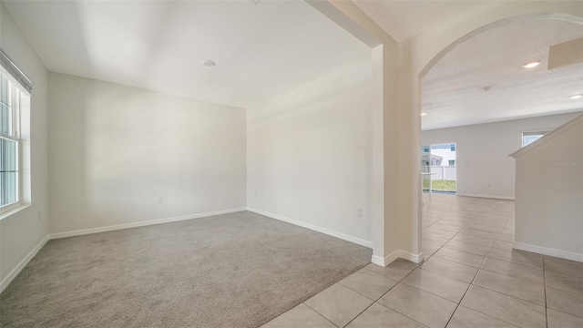 12732 Lateral Root Dr, Sarasota, FL 34238 - carpeted empty room featuring arched walkways, baseboards, tile patterned flooring, and recessed lighting