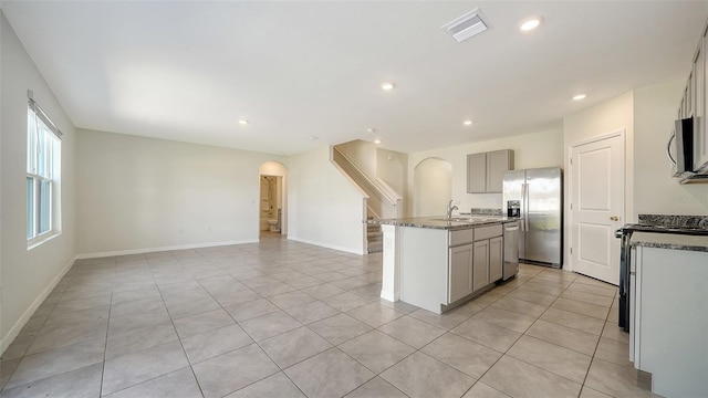 12732 Lateral Root Dr, Sarasota, FL 34238 - kitchen with stainless steel appliances, arched walkways, gray cabinets, a sink, and a kitchen island with sink
