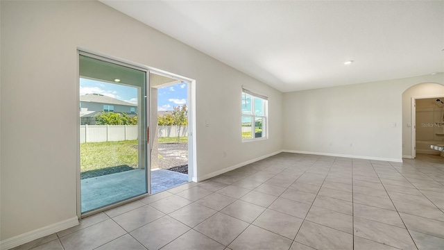 12732 Lateral Root Dr, Sarasota, FL 34238 - empty room with light tile patterned floors, arched walkways, and baseboards