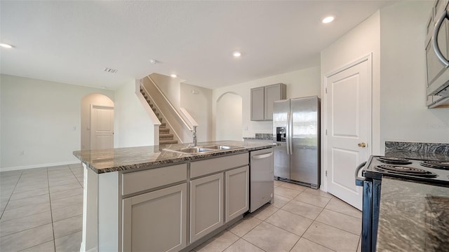 12732 Lateral Root Dr, Sarasota, FL 34238 - kitchen with stainless steel appliances, arched walkways, a sink, gray cabinets, and light tile patterned flooring