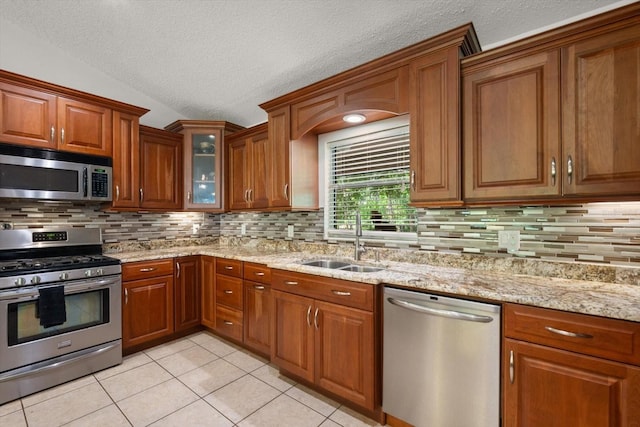13719 Seminole Trl, Wimauma, FL 33598 - kitchen featuring stainless steel appliances, a sink, light tile patterned flooring, a textured ceiling, and brown cabinetry