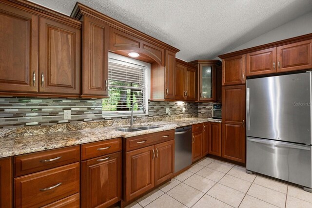 13719 Seminole Trl, Wimauma, FL 33598 - kitchen with appliances with stainless steel finishes, a sink, light tile patterned floors, a textured ceiling, and brown cabinets