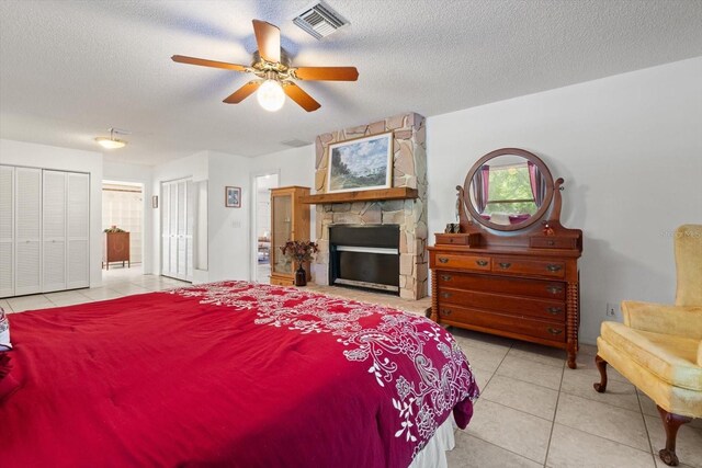 13719 Seminole Trl, Wimauma, FL 33598 - tiled bedroom with multiple closets, a textured ceiling, a fireplace, and ceiling fan